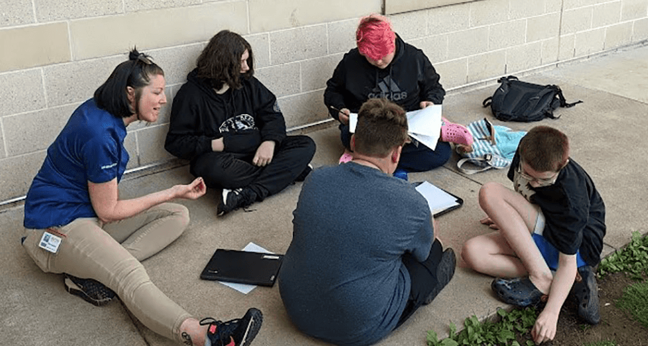 Photo of a PA Dream Team - Lehigh Valley member and four students sitting on concrete and talking